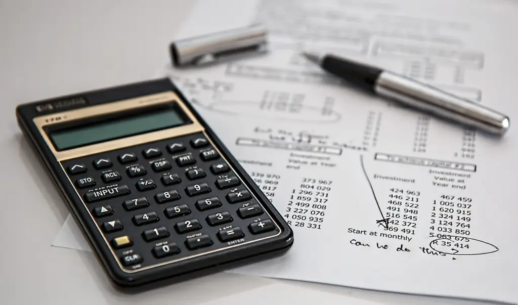 Calculator and cost documents on a desk for cost-plus pricing calculation