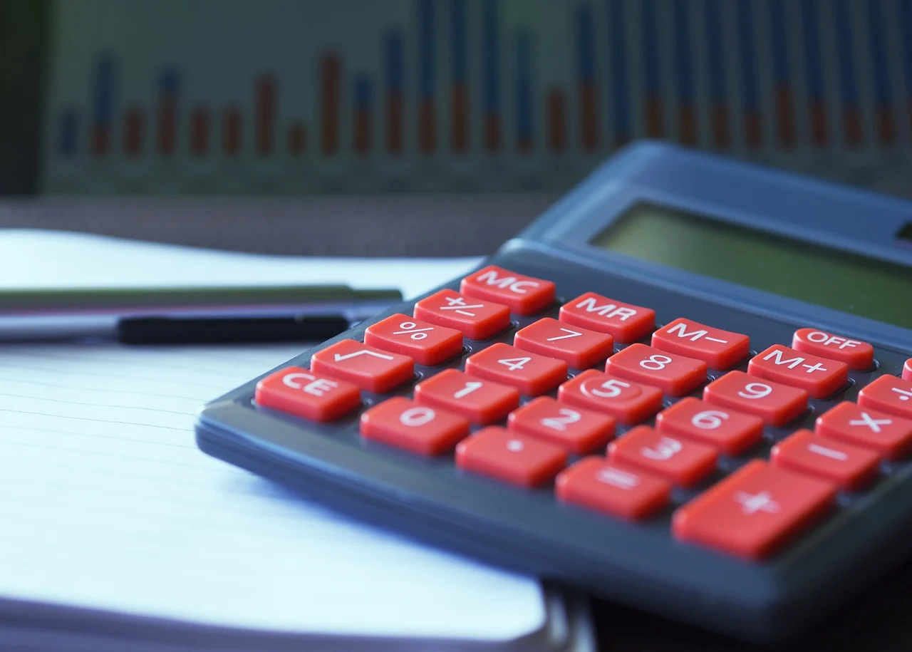 Calculator on a business desk with notebook and pen showing break-even calculation