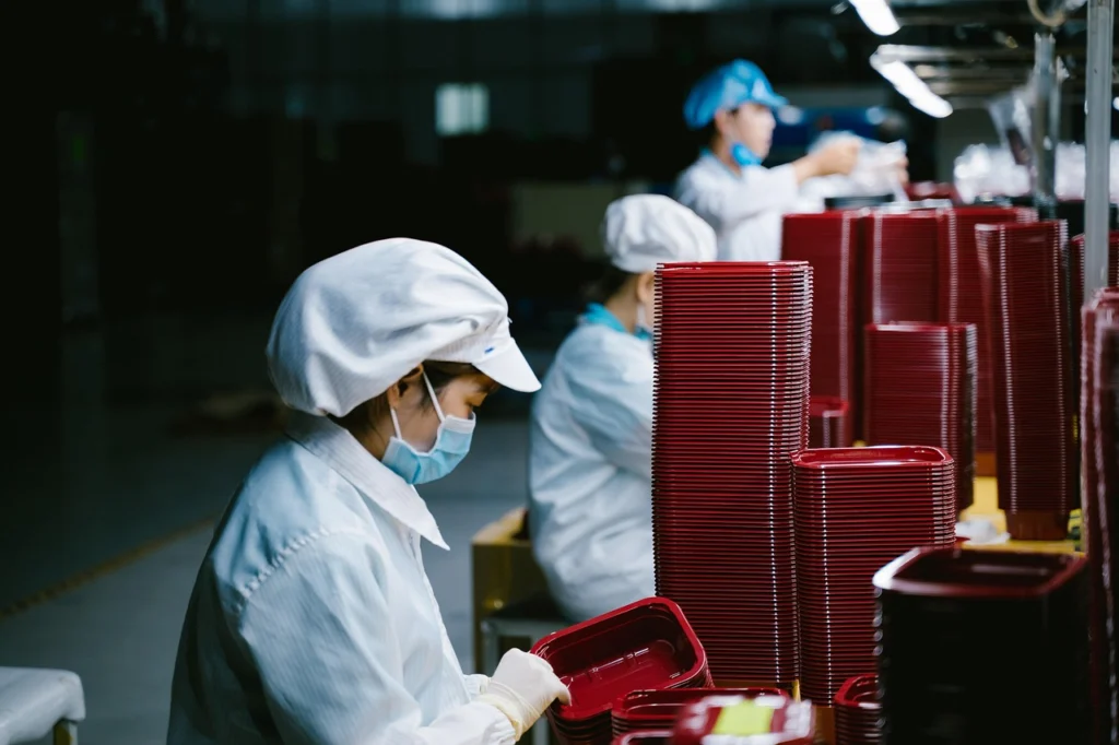 Factory production line with workers and machines, representing manufacturing costs